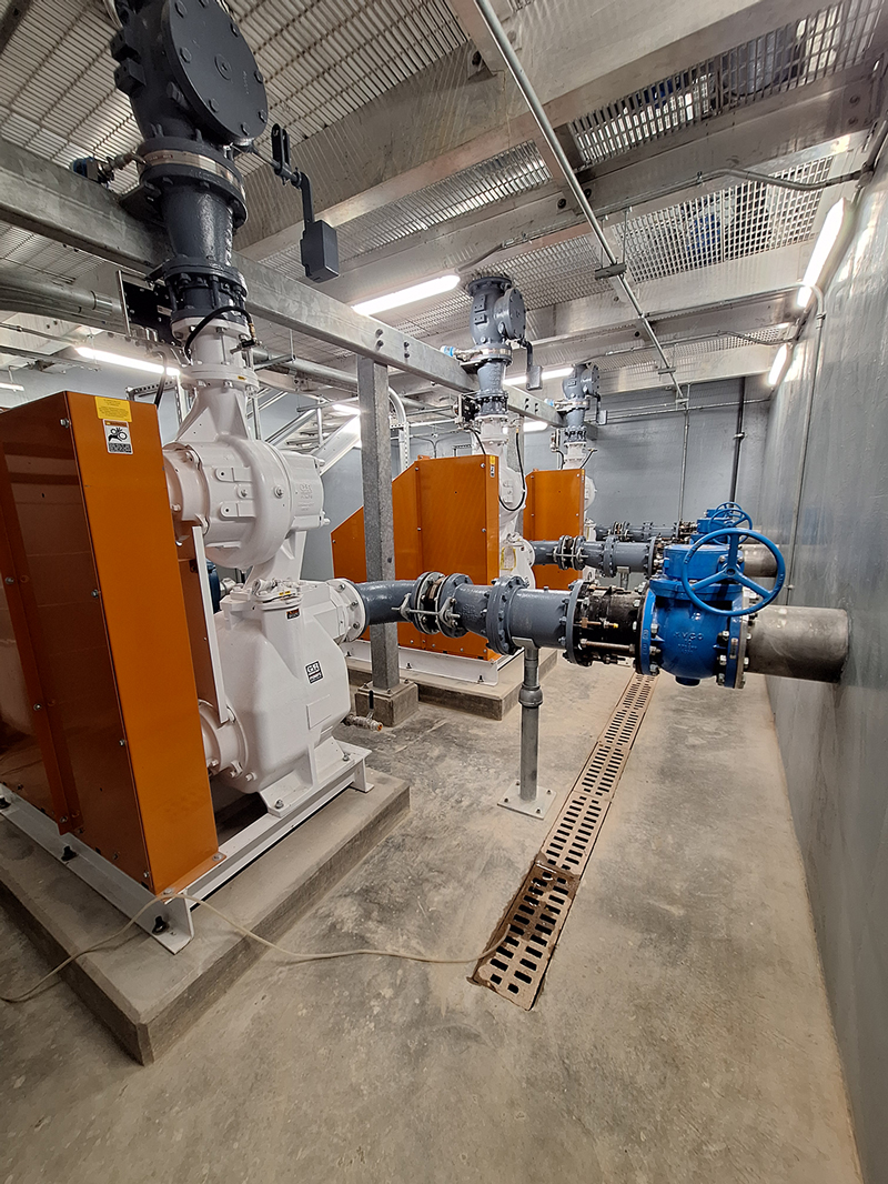 Interior of the New Piney Pump Station showing self-priming sewer pumps, motor control panels, piping, and gate valves at Water Authority of Dickson County's regional lift station.